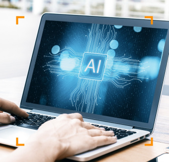 ersona che digita sulla tastiera di un laptop, sul cui schermo è visibile una grafica digitale con un microchip luminoso e la scritta "AI".